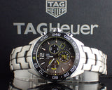 Silver TAG Heuer watch with black dial and bracelet.