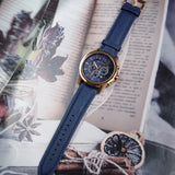 Blue and gold wristwatch on a book, with dried fruit.