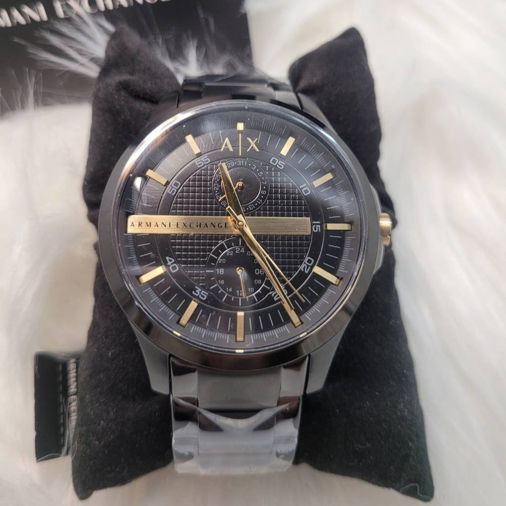 Black and gold Armani Exchange wristwatch on a black cushion.