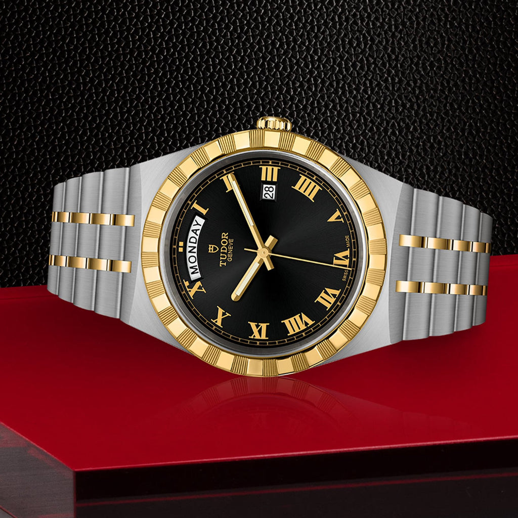 Silver and gold wristwatch with black face and Roman numerals.