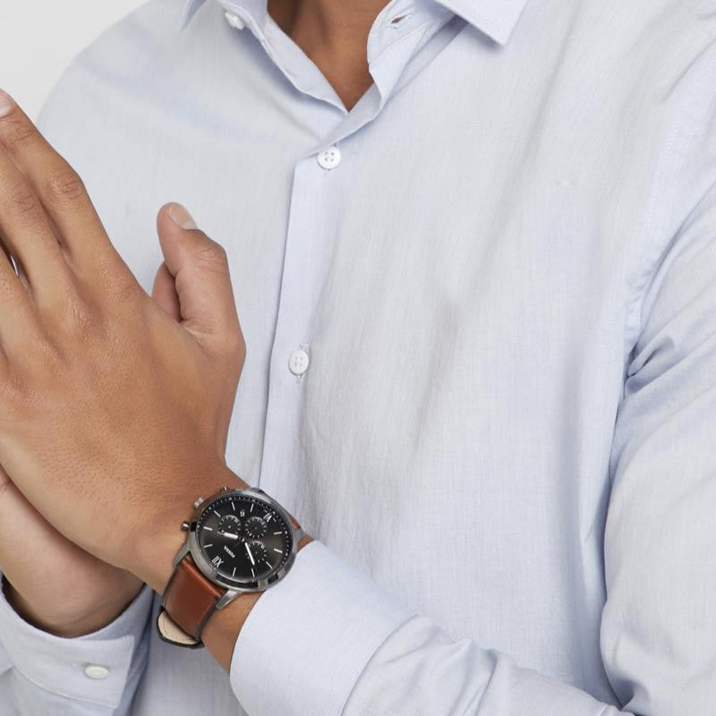 Man wearing a watch with a brown leather strap and light blue shirt