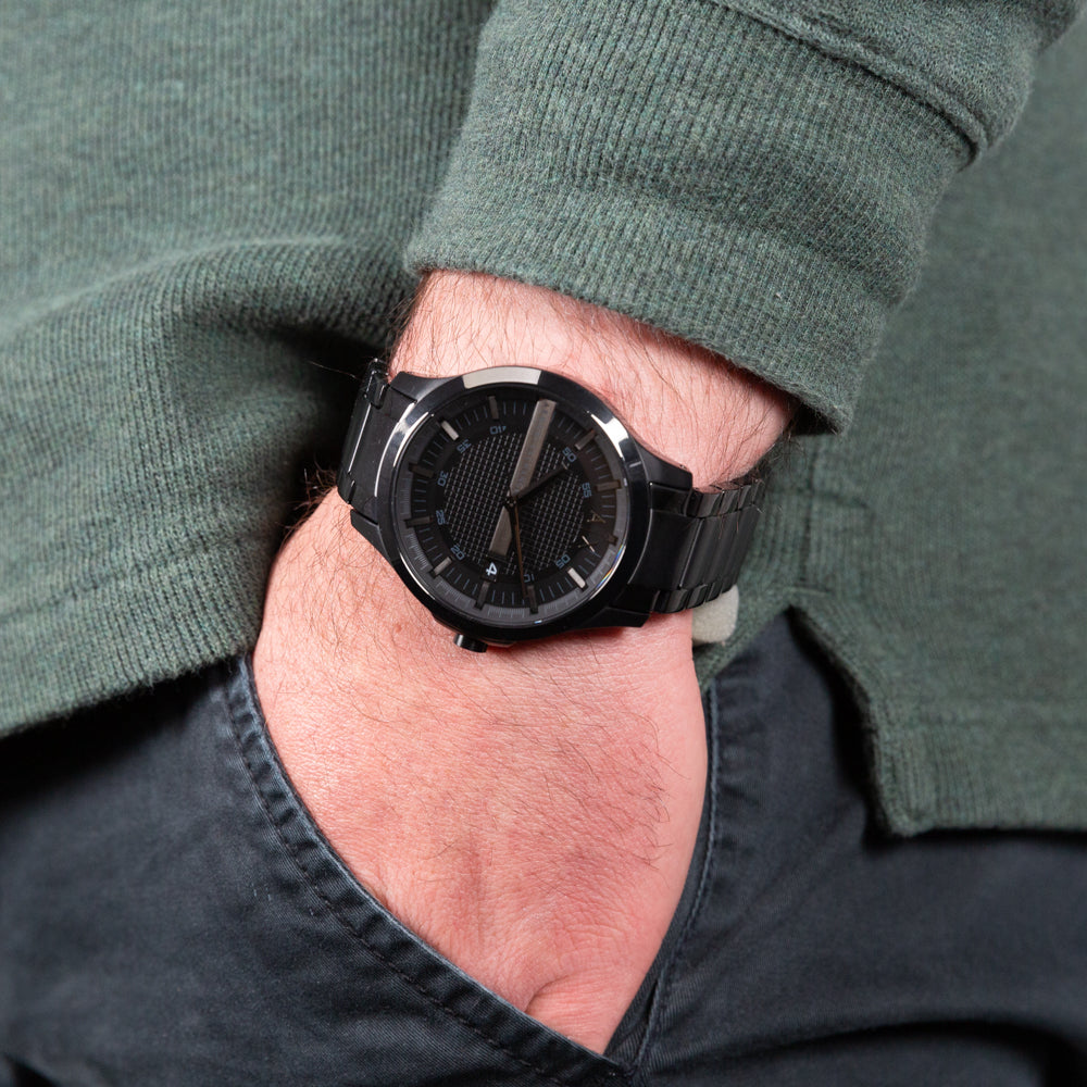 Man's wrist with a black watch and hand in pocket.