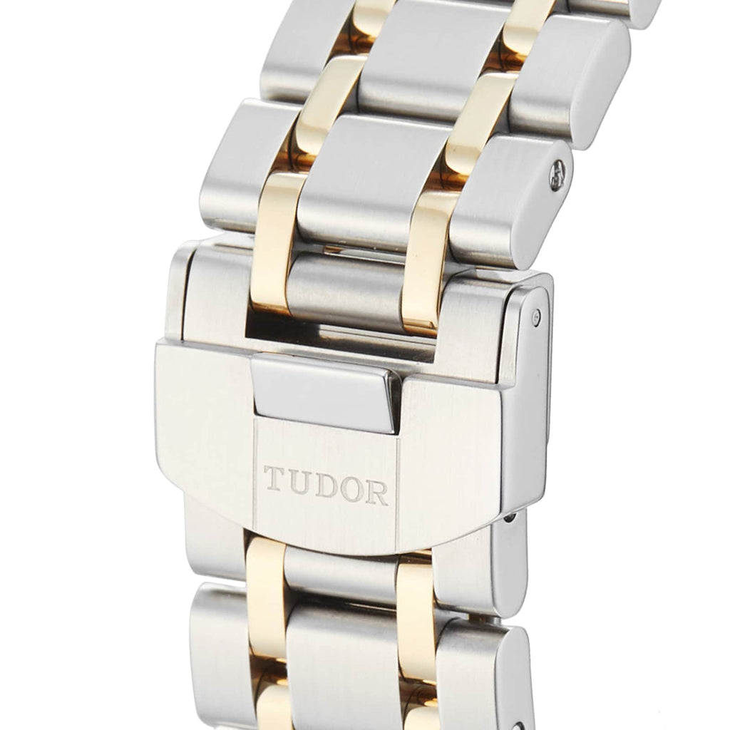 Close-up of a silver and gold watch band with TUDOR engraved.