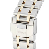 Close-up of a silver and gold watch band with TUDOR engraved.