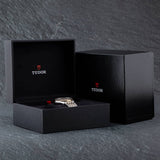 Black watch box with Tudor watch inside.