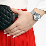 Silver watch on wrist with red skirt and black bag