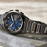 Black wristwatch with blue accents on a concrete surface.