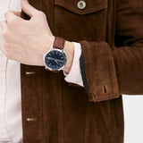 Man wearing a watch and brown jacket.