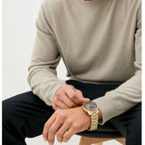 Person wearing a gold wristwatch.