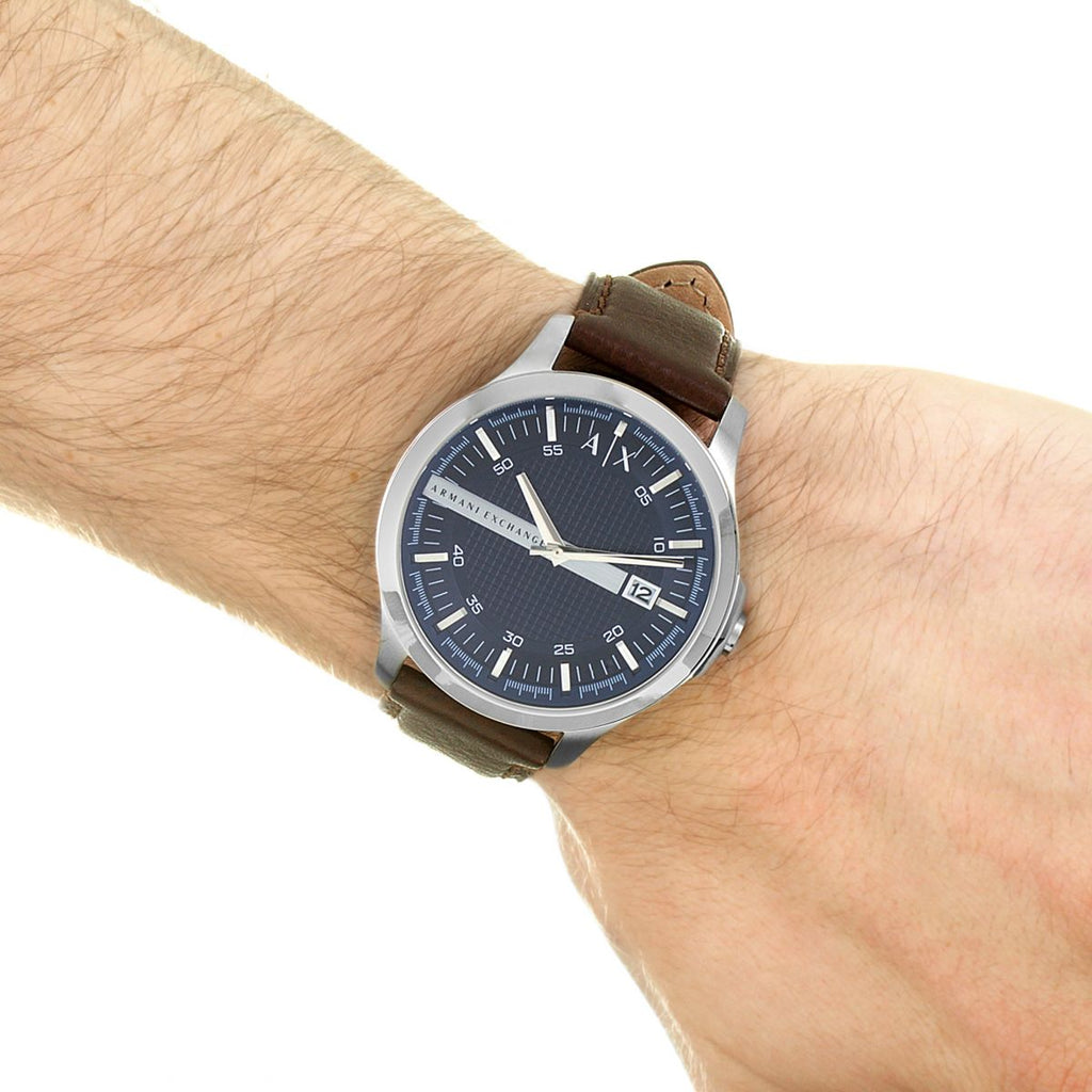 Wrist with a silver watch and brown leather strap.