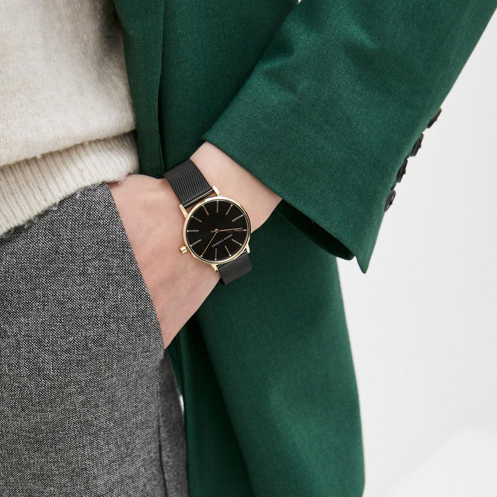 AX5548-5 black watch on wrist with gold accents, green jacket.