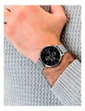 Men's watch on wrist with black face and silver band