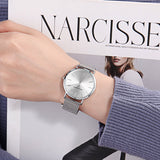 Silver wristwatch on wrist with Narcisse magazine