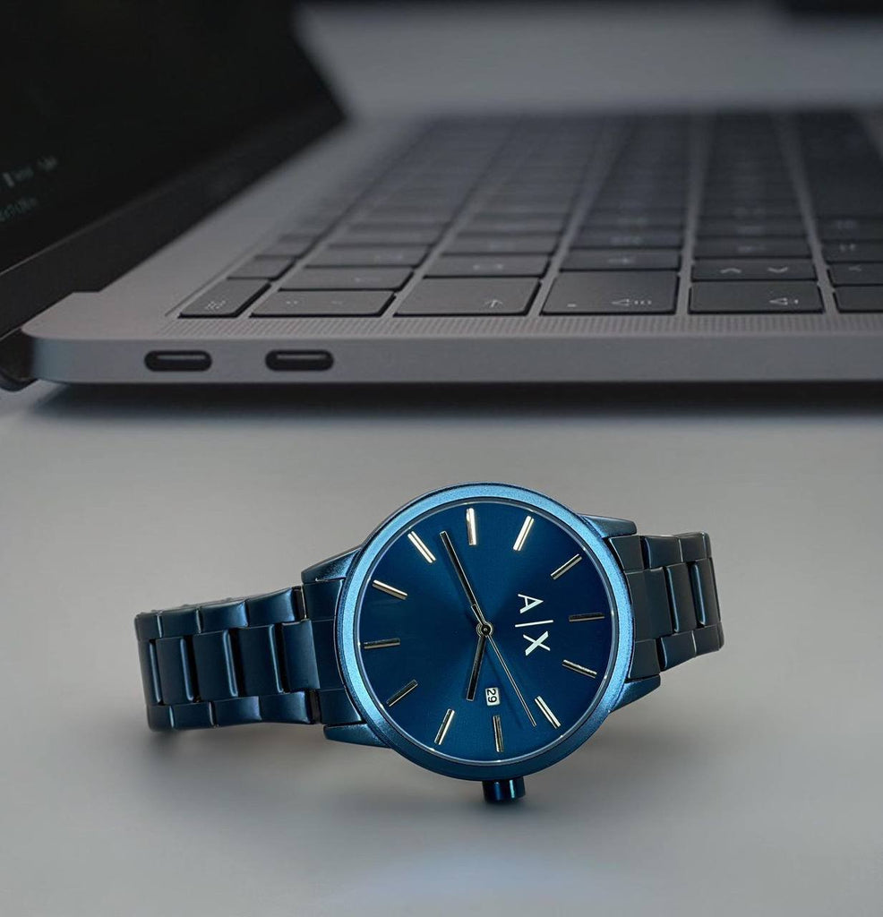 Blue AX watch on table with laptop