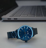 Blue AX watch on table with laptop