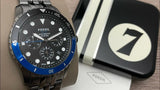 Fossil watch with blue bezel, black dial, and Fossil watch box.