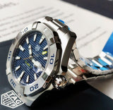 TAG Heuer Aquaracer watch with blue face and silver bracelet.
