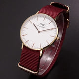 Gold wristwatch with burgundy strap.