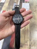 Hand holding a black wristwatch.