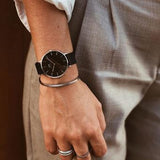 Wrist with watch, bracelet, and rings.