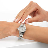Woman's wrist with a silver wristwatch and another hand touching it.