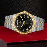 Silver and gold wristwatch with black face and Roman numerals.