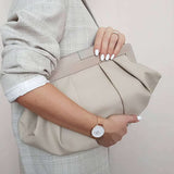 Woman holding beige clutch purse