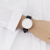 Wrist with watch on a white shirt.