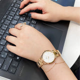 Person typing on laptop with gold watch.