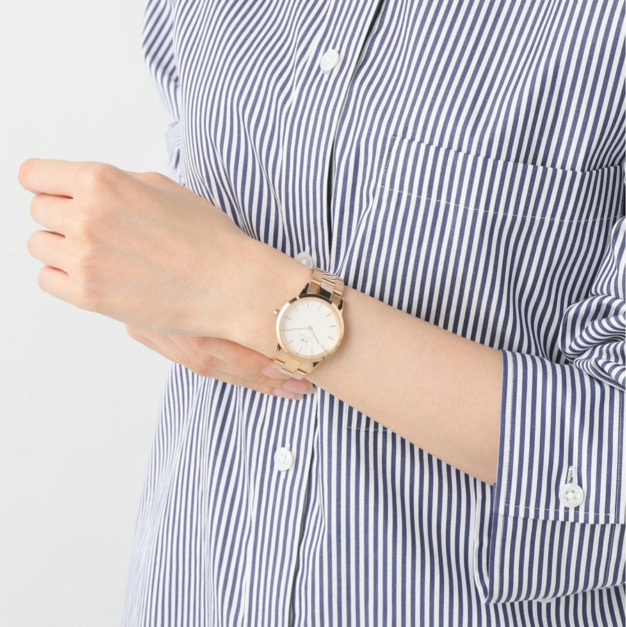 Woman wearing a gold wristwatch and striped shirt.