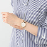 Woman wearing a gold wristwatch and striped shirt.