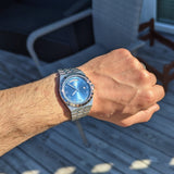Man's wrist with blue-faced watch, 302a7aa4-8ff8
