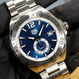 Silver wristwatch with blue face and date display.