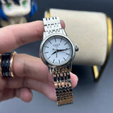 Silver wristwatch with white face held by a hand.