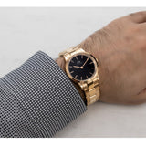 Man wearing a gold wristwatch with a black face.