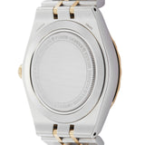 Back of a silver and gold watch with text.