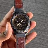 Fossil watch with brown leather band, held in hand