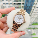 Rose gold wristwatch on a white cushion.