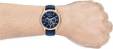 AX watch on wrist with blue strap and gold face.