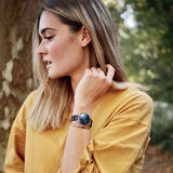 Woman wearing a watch and a yellow shirt.