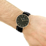 Wrist with a black watch and leather band.