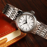 Tissot watch with silver band and white face on wood