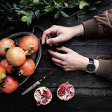 Pomegranates & hands on a dark wood surface