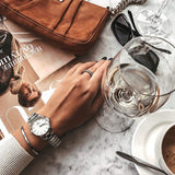 Stylish woman's hand with watch, wine glass and accessories.