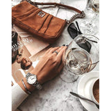 Woman's hand with watch, bag, and wine glass