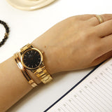 Gold watch and bracelet on wrist