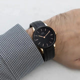 Daniel Wellington watch DW00100425-4 on wrist with black face and gold accents.