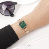 Rose gold watch with green face on wrist