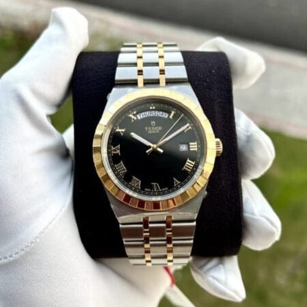 Tudor watch with black dial, gold accents, and silver band.