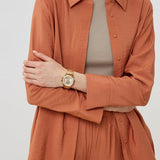 Woman wearing orange shirt and gold watch